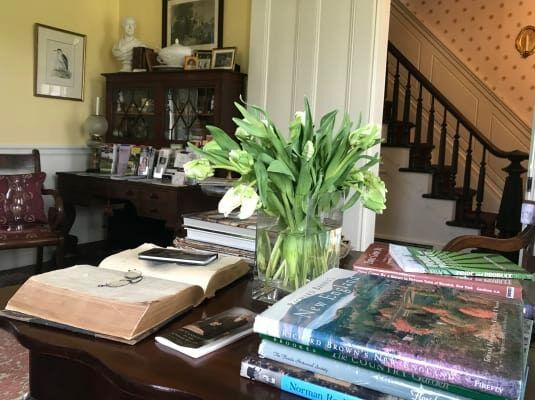 A vase of flowers sits on a table next to a stack of books