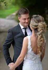 A bride and groom are holding hands and looking at each other.