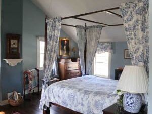 A bedroom with a canopy bed and blue and white curtains.