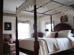 A bedroom with a four poster bed and a chair.