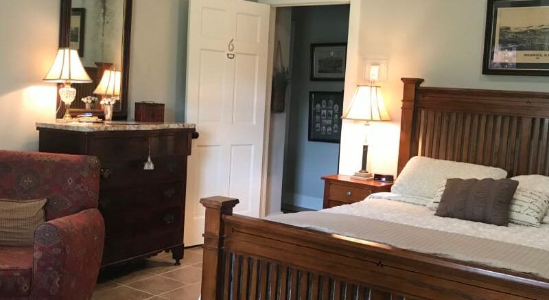 A bedroom with a bed , dresser , chair and mirror.