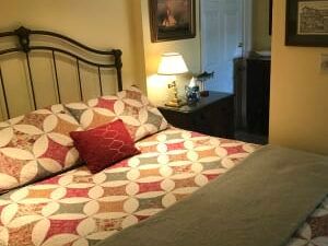 A bedroom with a bed , nightstand , lamp and picture on the wall.