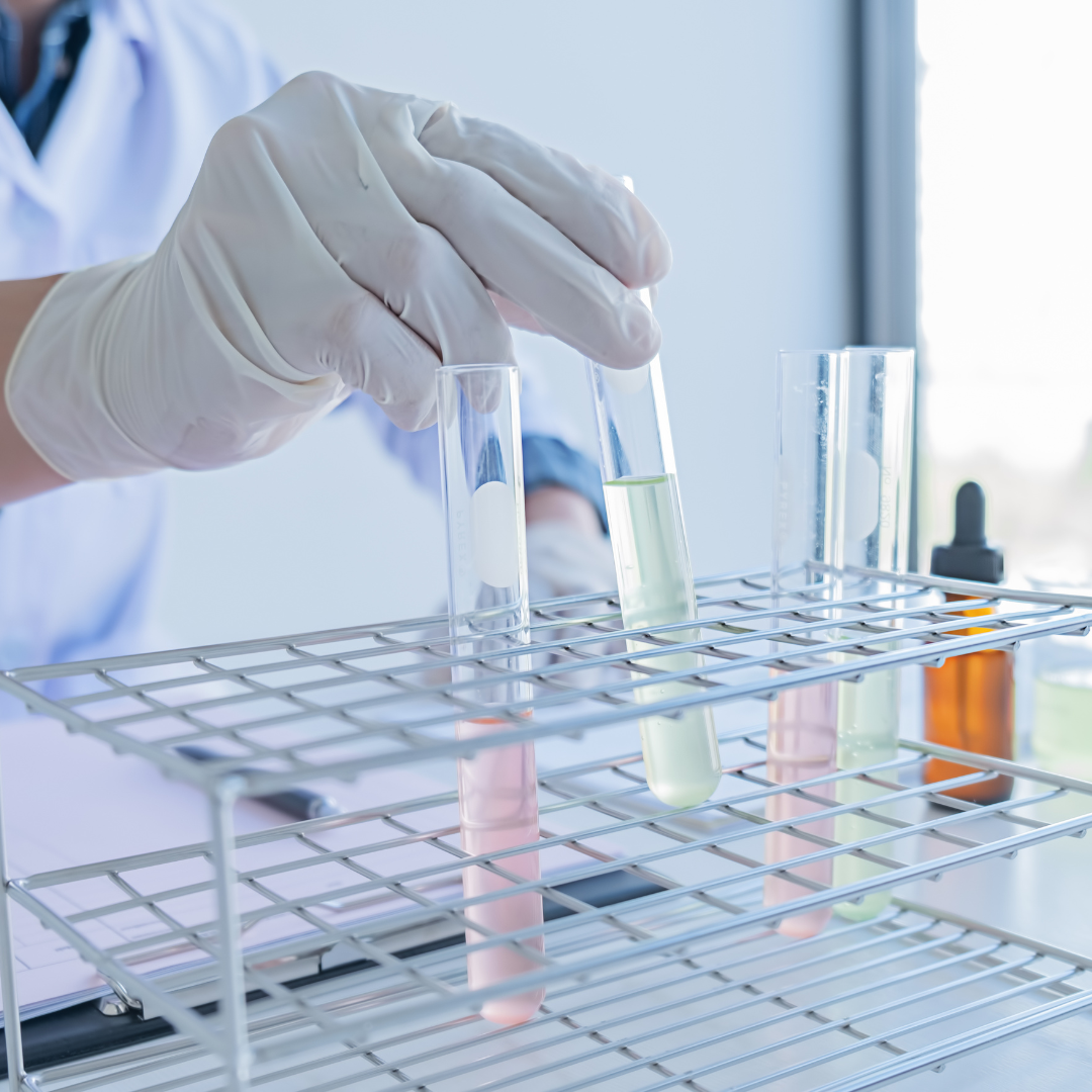 A person is holding a test tube over a rack of test tubes.