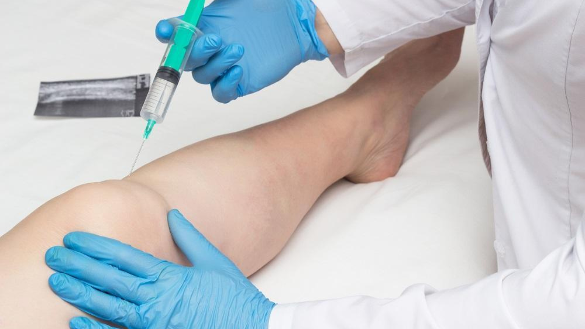 Woman smiles, reclining on a beige sofa, looking off-screen.