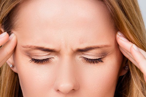 A woman is holding her head because she has a headache.