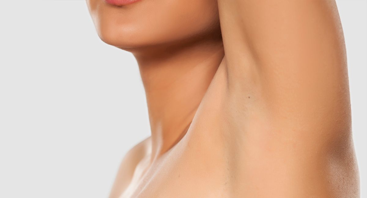 A close up of a woman 's armpit with a gray background.