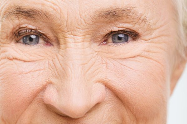 A close up of an elderly woman 's face with wrinkles and blue eyes.