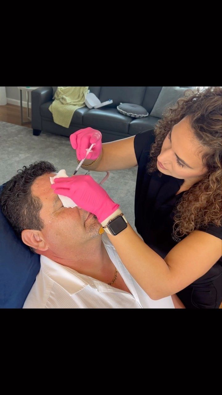 A woman is applying botox to a man 's forehead.
