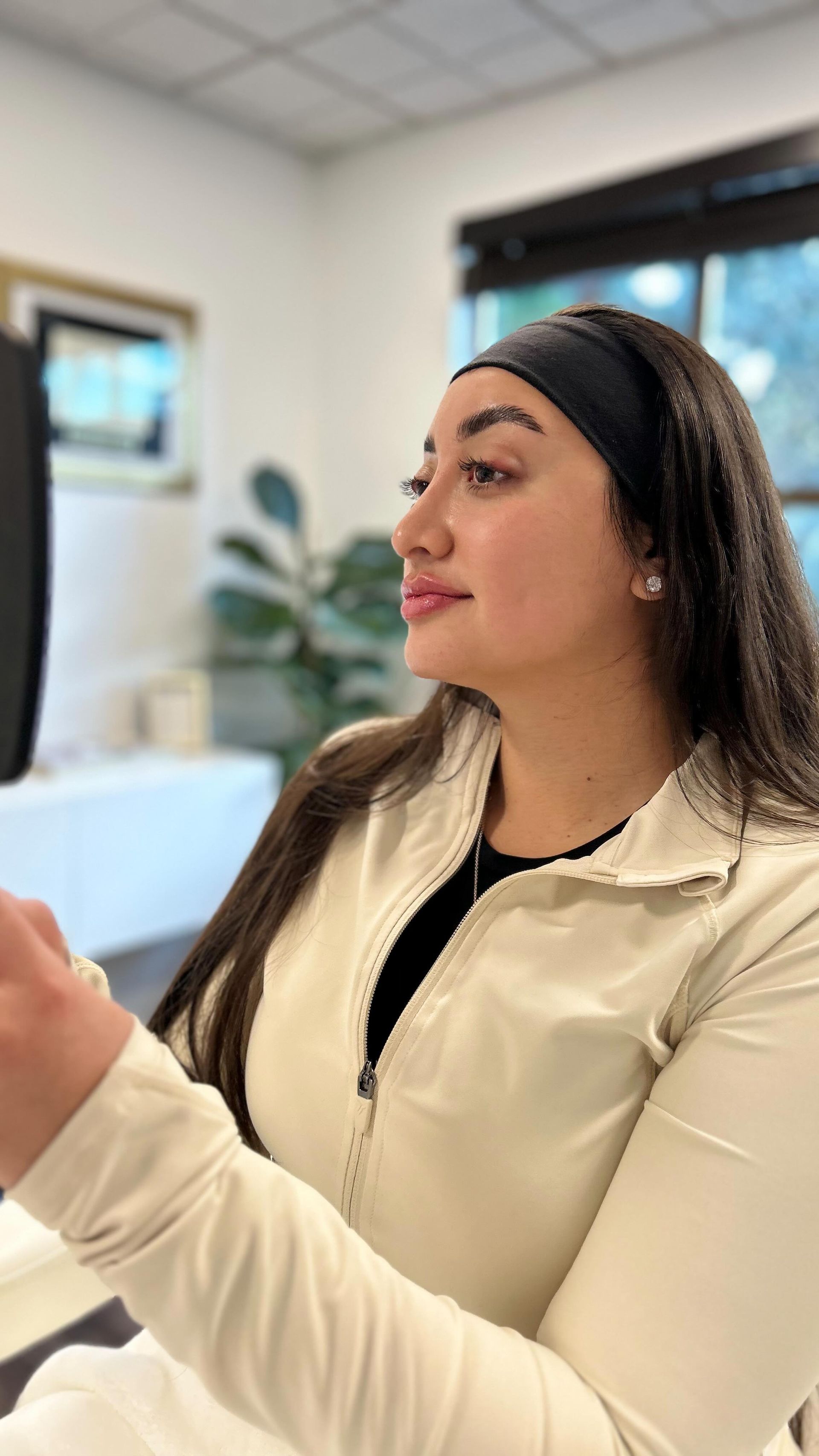 A woman wearing a headband and a white jacket is sitting in a room.