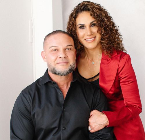 A man and a woman are posing for a picture together . the woman is wearing a red jacket.