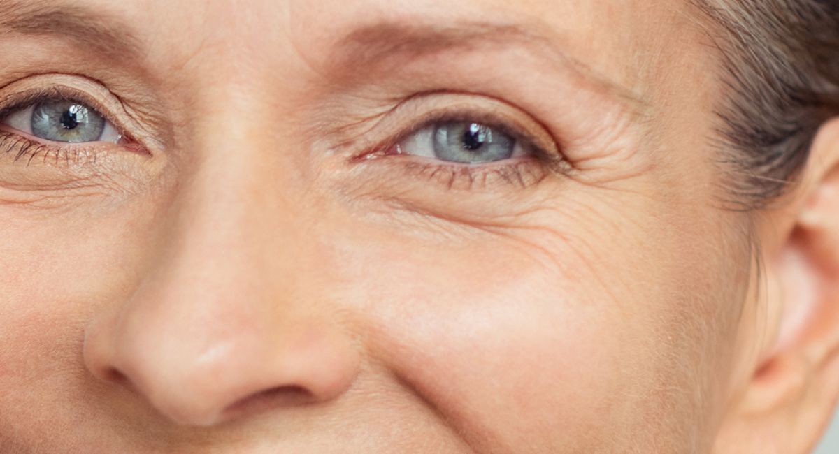 A close up of an older woman 's face with blue eyes and wrinkles.