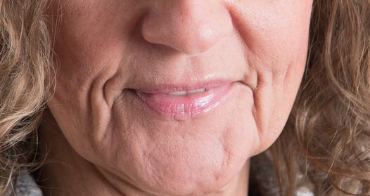 A close up of a woman 's face with wrinkles and a smile.