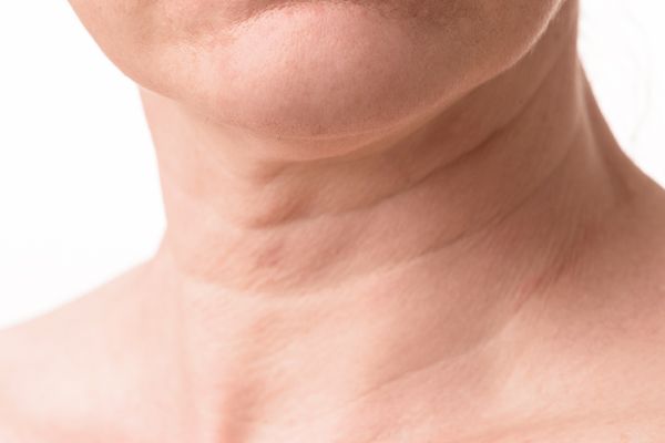 A close up of a woman 's neck and neckline on a white background.