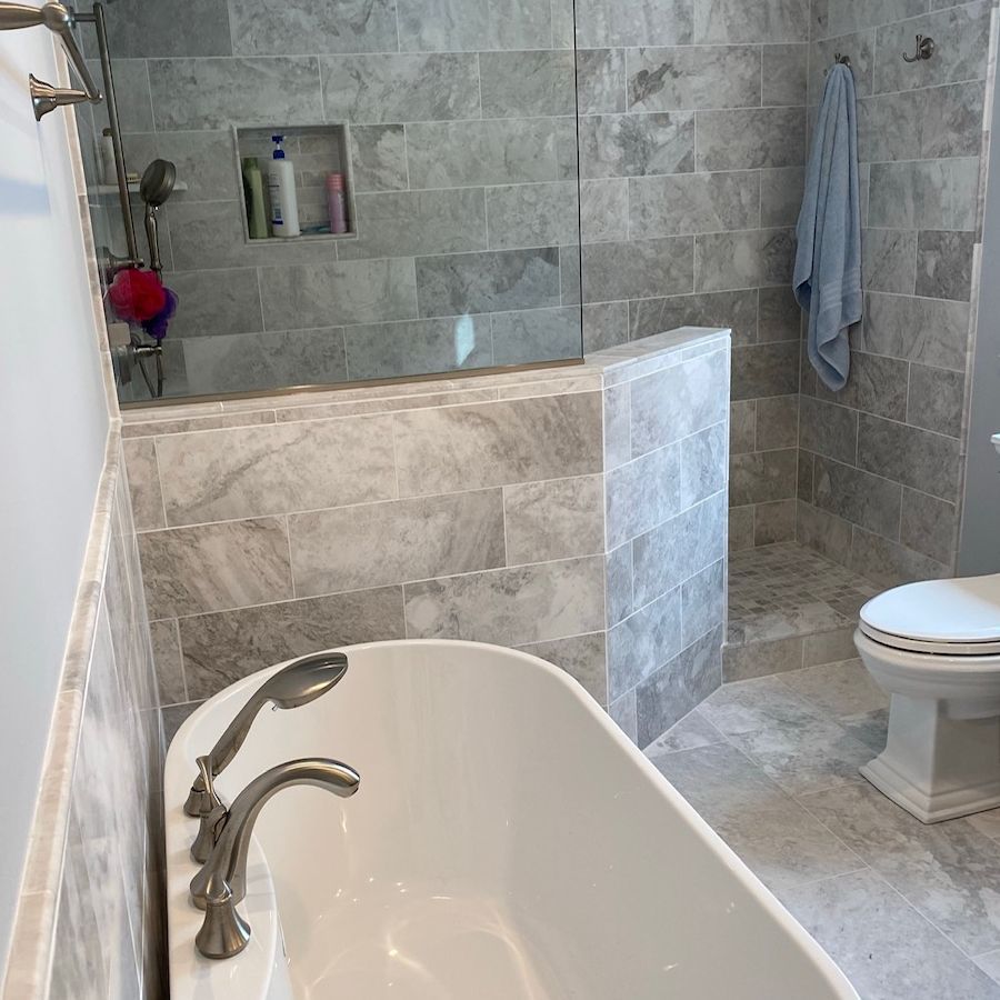 A bathroom with a tub , toilet and shower