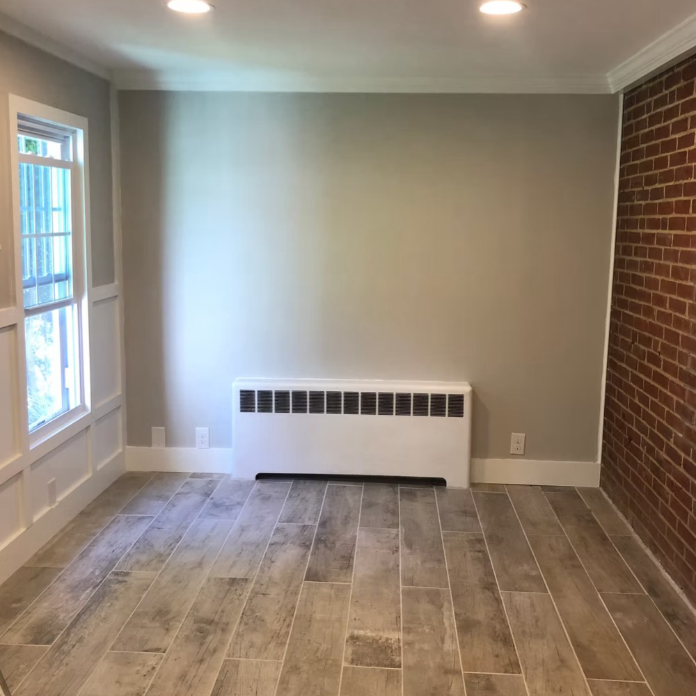An empty room with a brick wall and a window