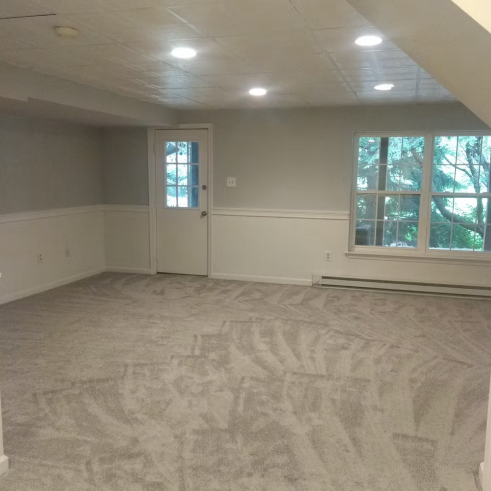 An empty room with a carpeted floor and a door