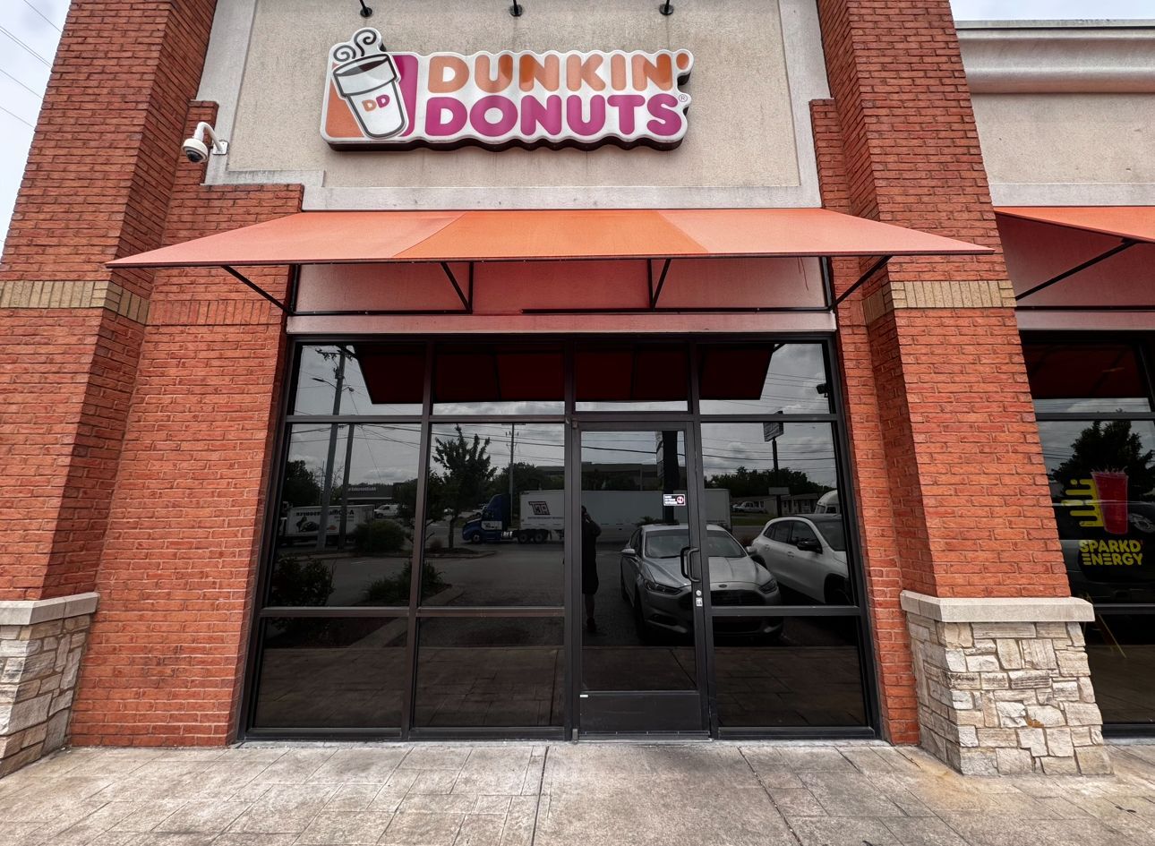 Two people buffing a car's chrome trim with electric polishers.
