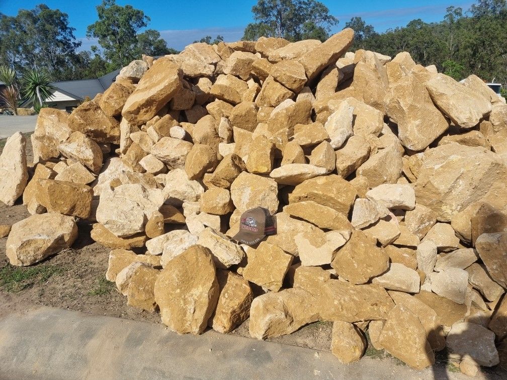 A pile of sandstone rocks is sitting on the side of the road.