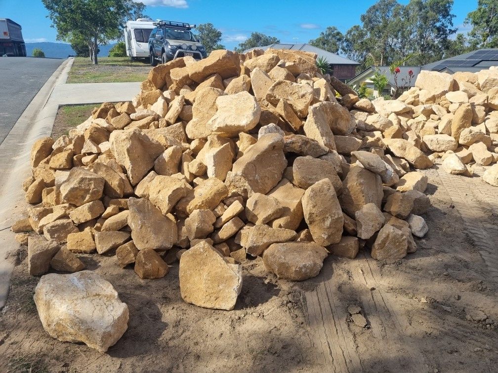 A pile of sandstone rocks is sitting on the side of a road.