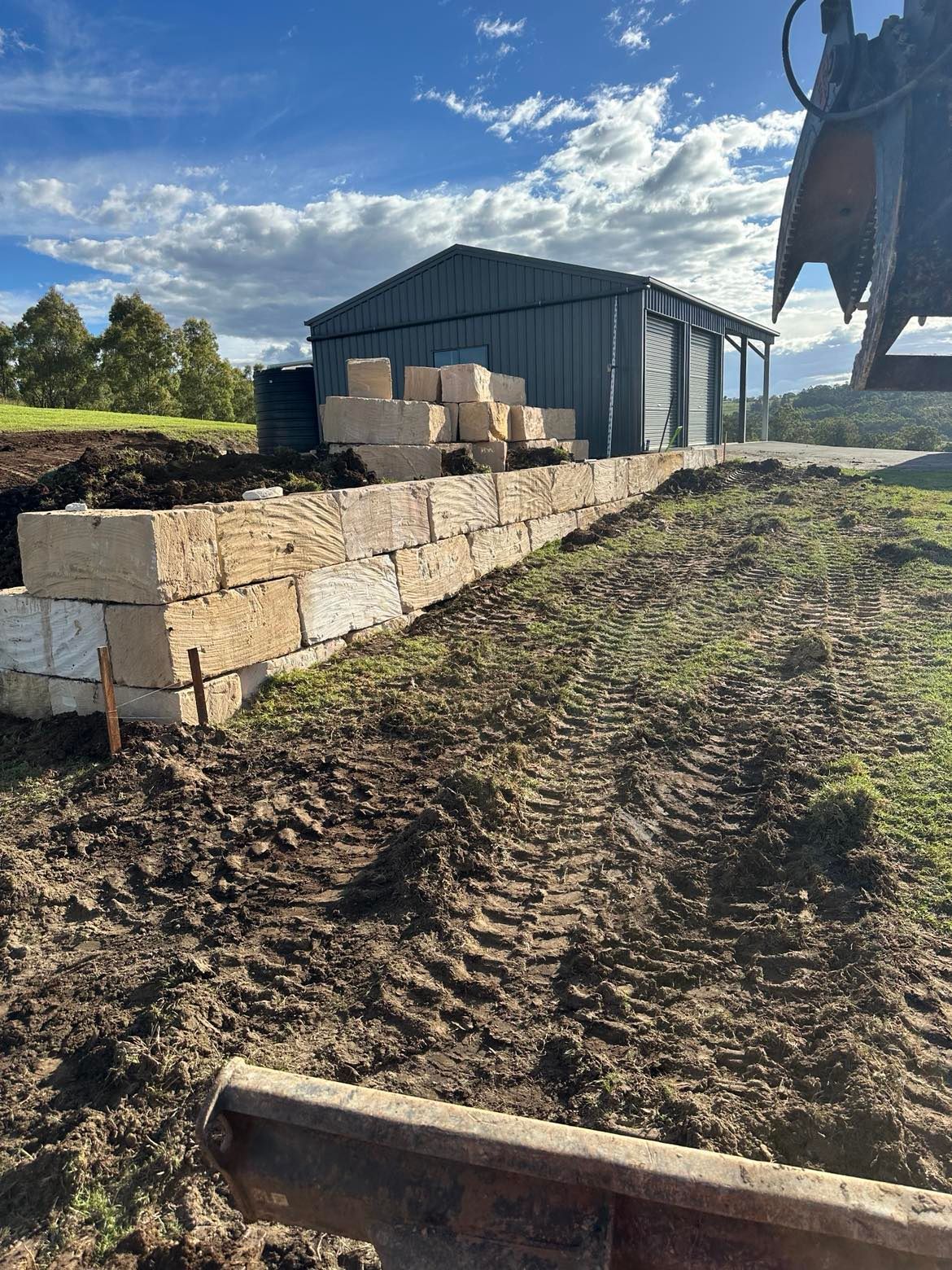 A large pile of sandstone bricks is sitting in the dirt in front of a building.