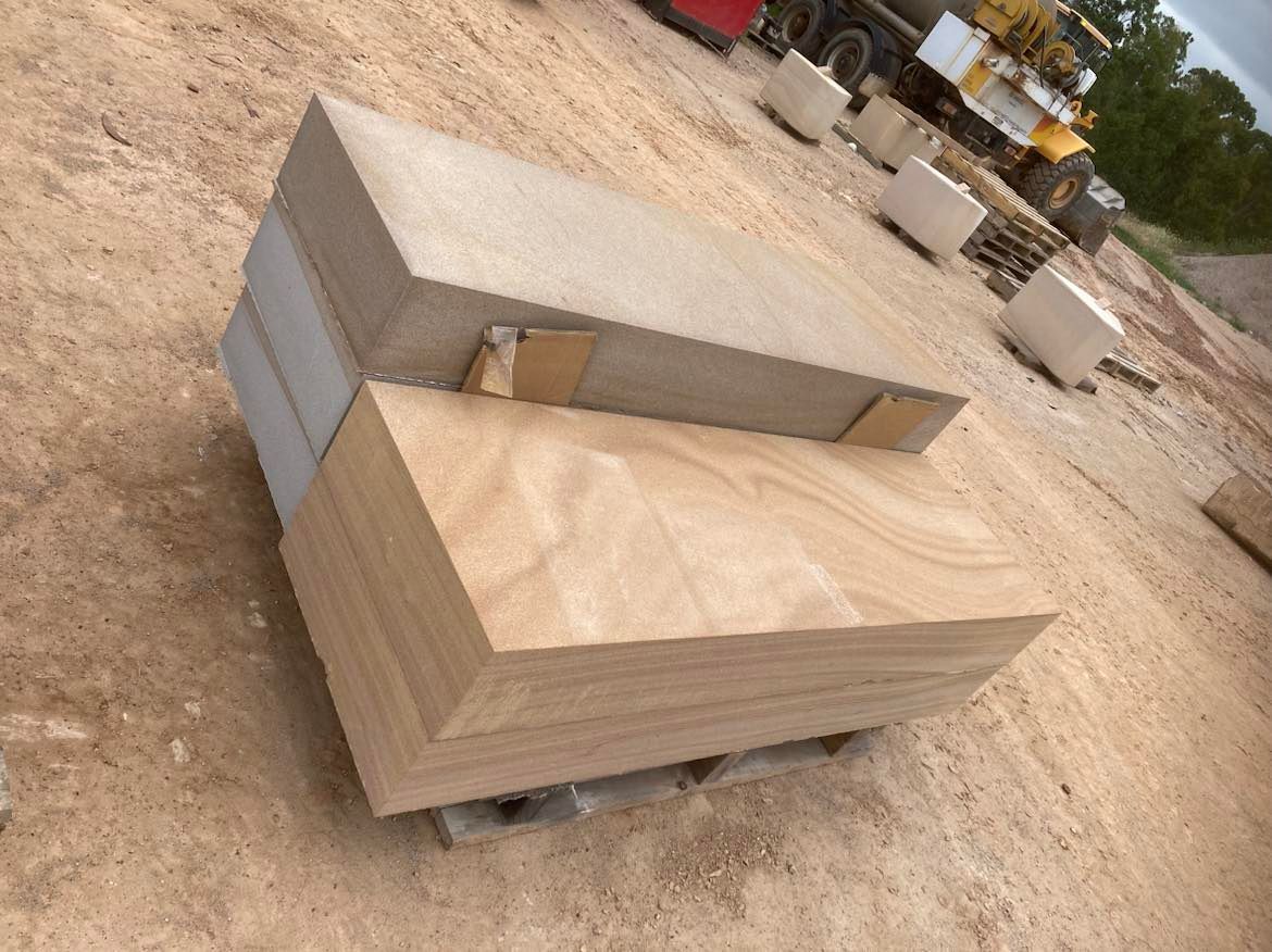 A stack of sandstone blocks sitting on top of each other on a dirt field.