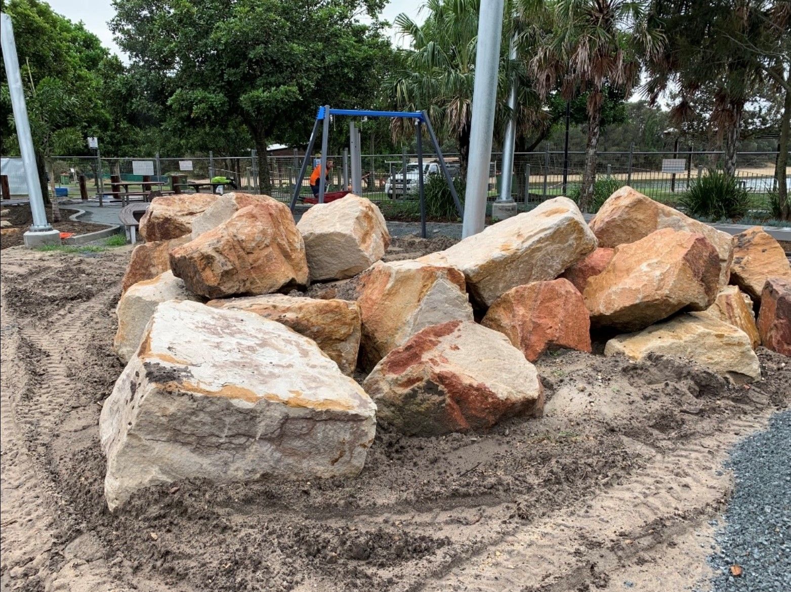 A pile of sandstone rocks is sitting in the dirt in a park.