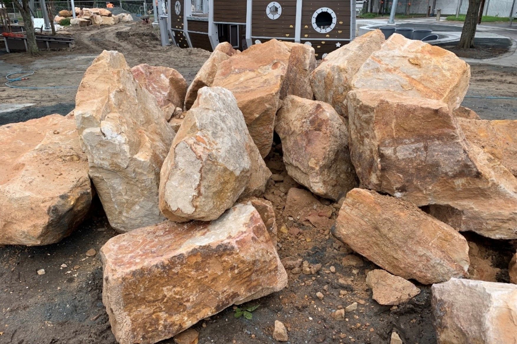 A pile of sandstone rocks is sitting on the ground in front of a house.