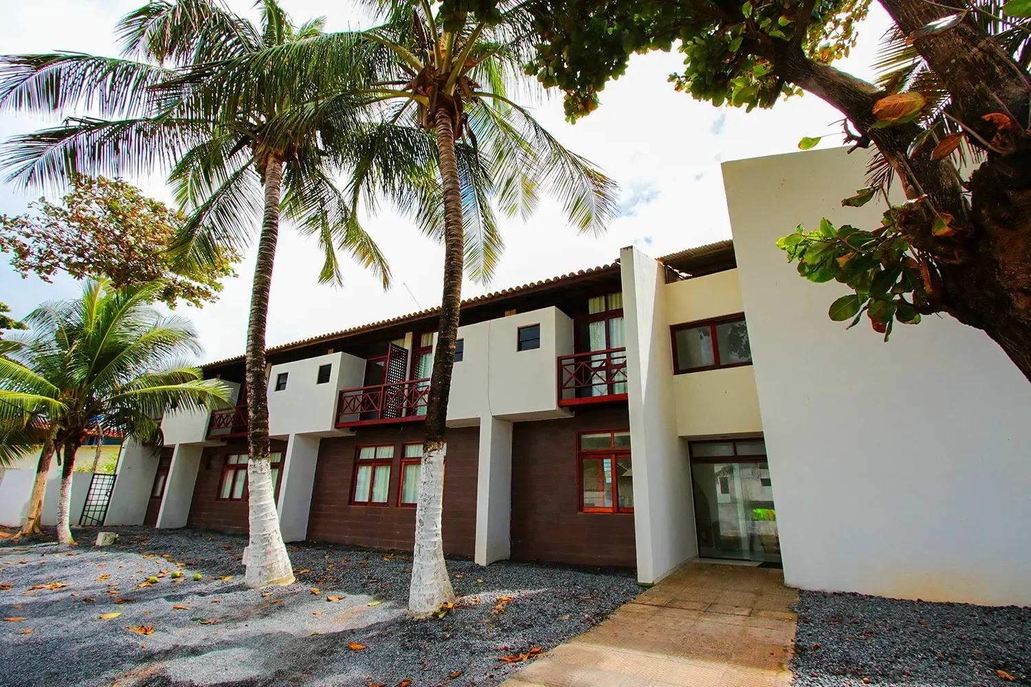 Um prédio branco com palmeiras na frente