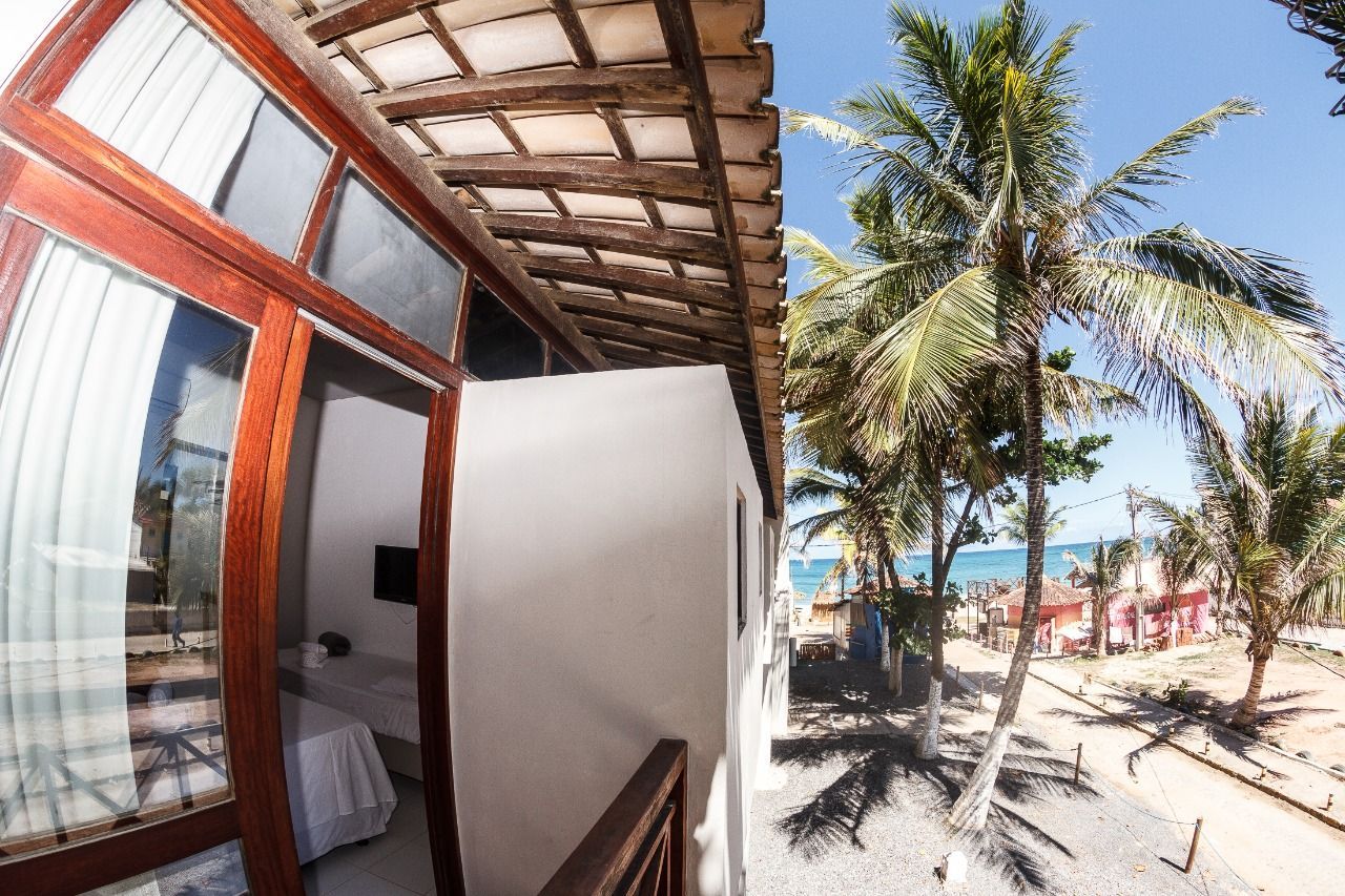 Um quarto com varanda com vista para o mar e palmeiras
