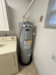 A water heater is sitting next to a washer and dryer in a laundry room.