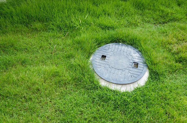 Manhole Cover in Green Grass | Residential Septic Services