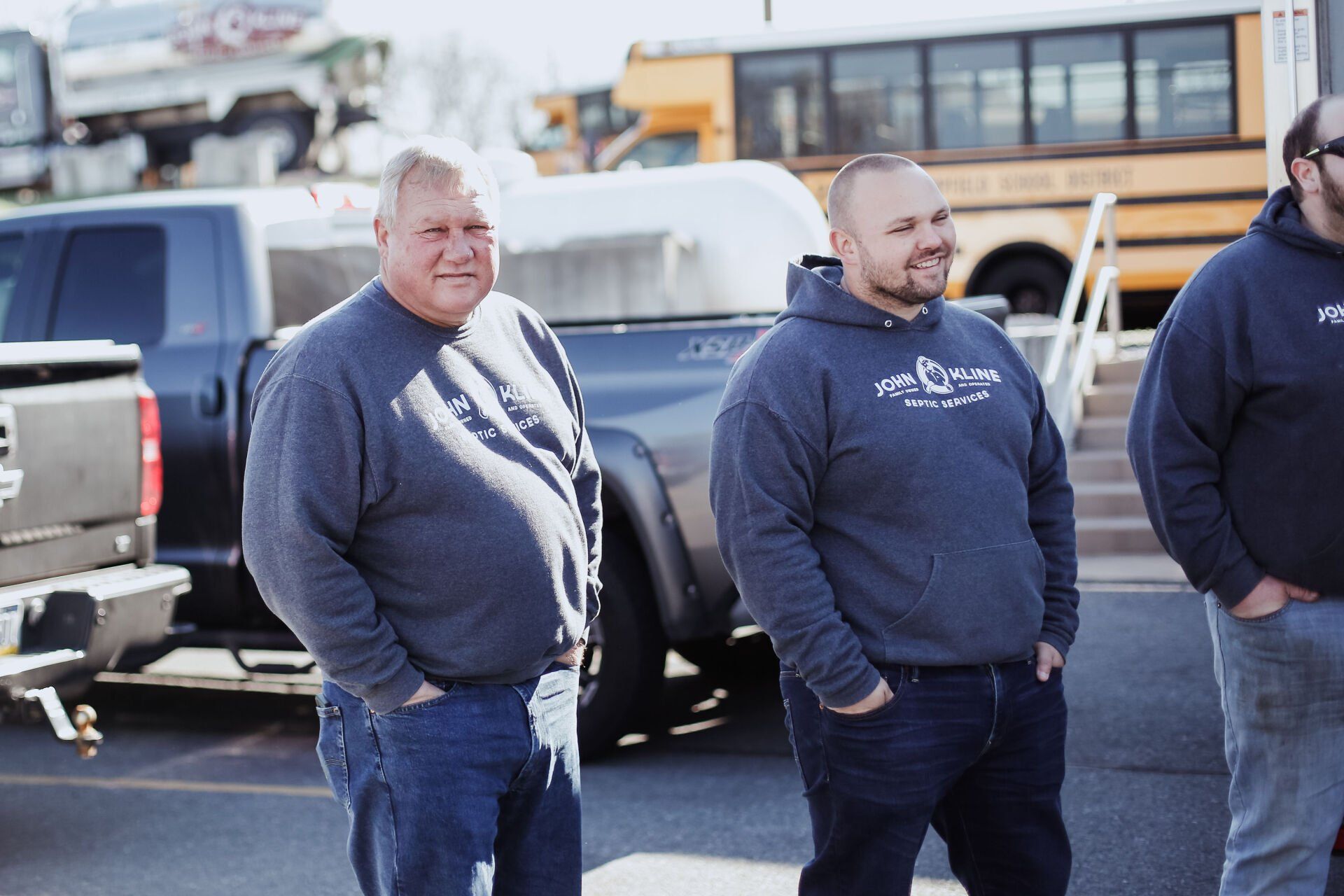 Three men are standing next to each other in a parking lot.