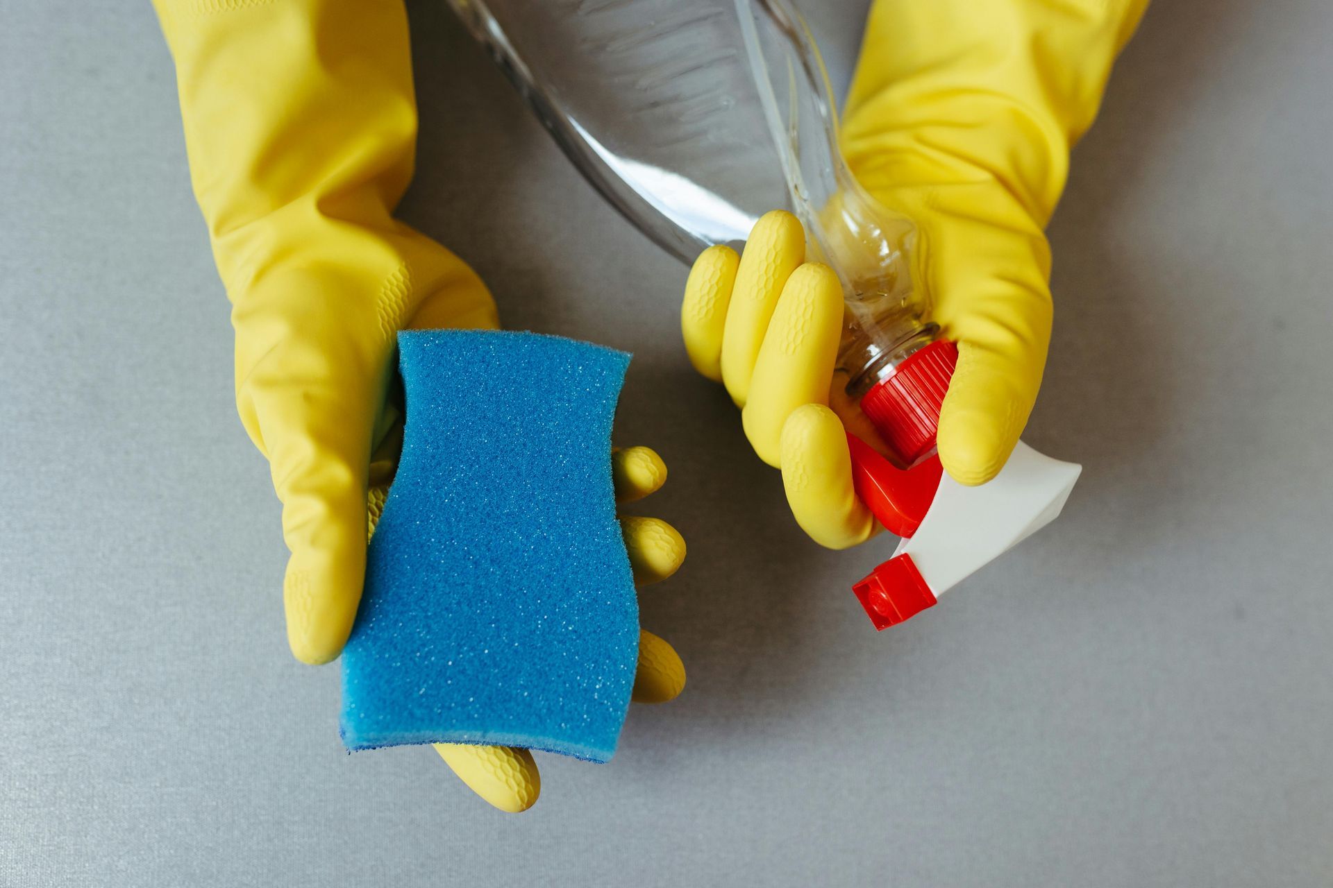 cleaning supplies featuring yellow gloves, blue sponge and spray bottle representing Spring Cleaning