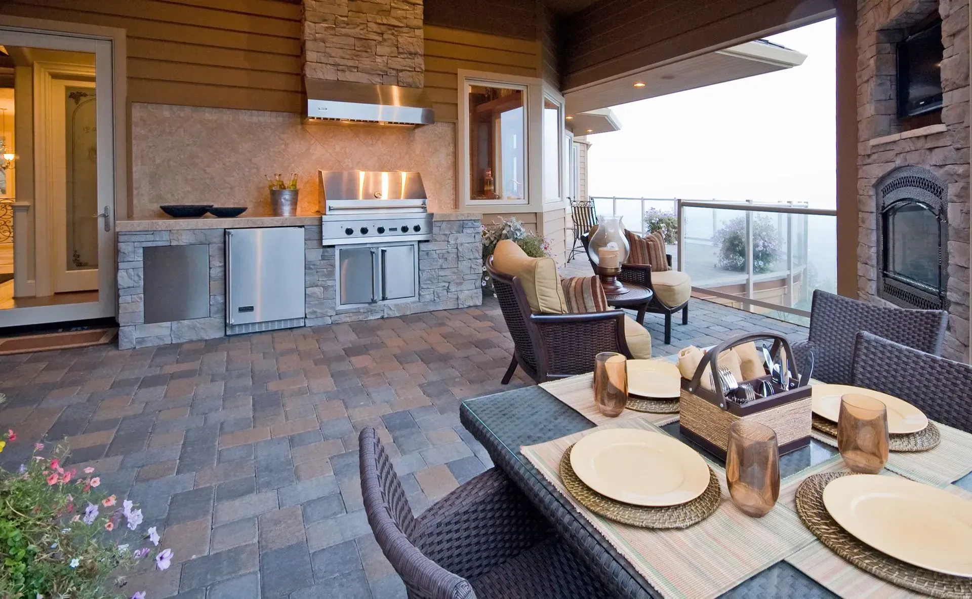 Outdoor patio with a built-in grill, dining table set for four, and cushioned seating overlooking the view