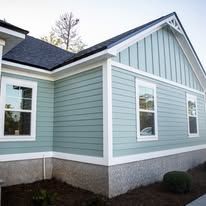 Light blue house with white trim and windows, gray foundation, and dark blue roof.