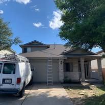 White van parked in front of a house with a blue sky and trees.
