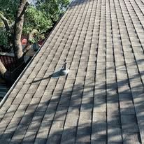 Close-up view of a weathered asphalt shingle roof under sunlight with shadows.