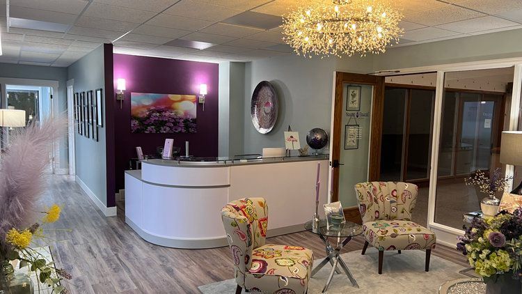 A living room with a reception desk , chairs , and a chandelier.