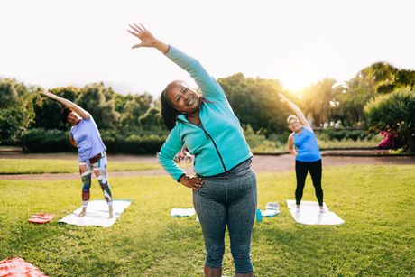 A group of women are doing yoga in a park.