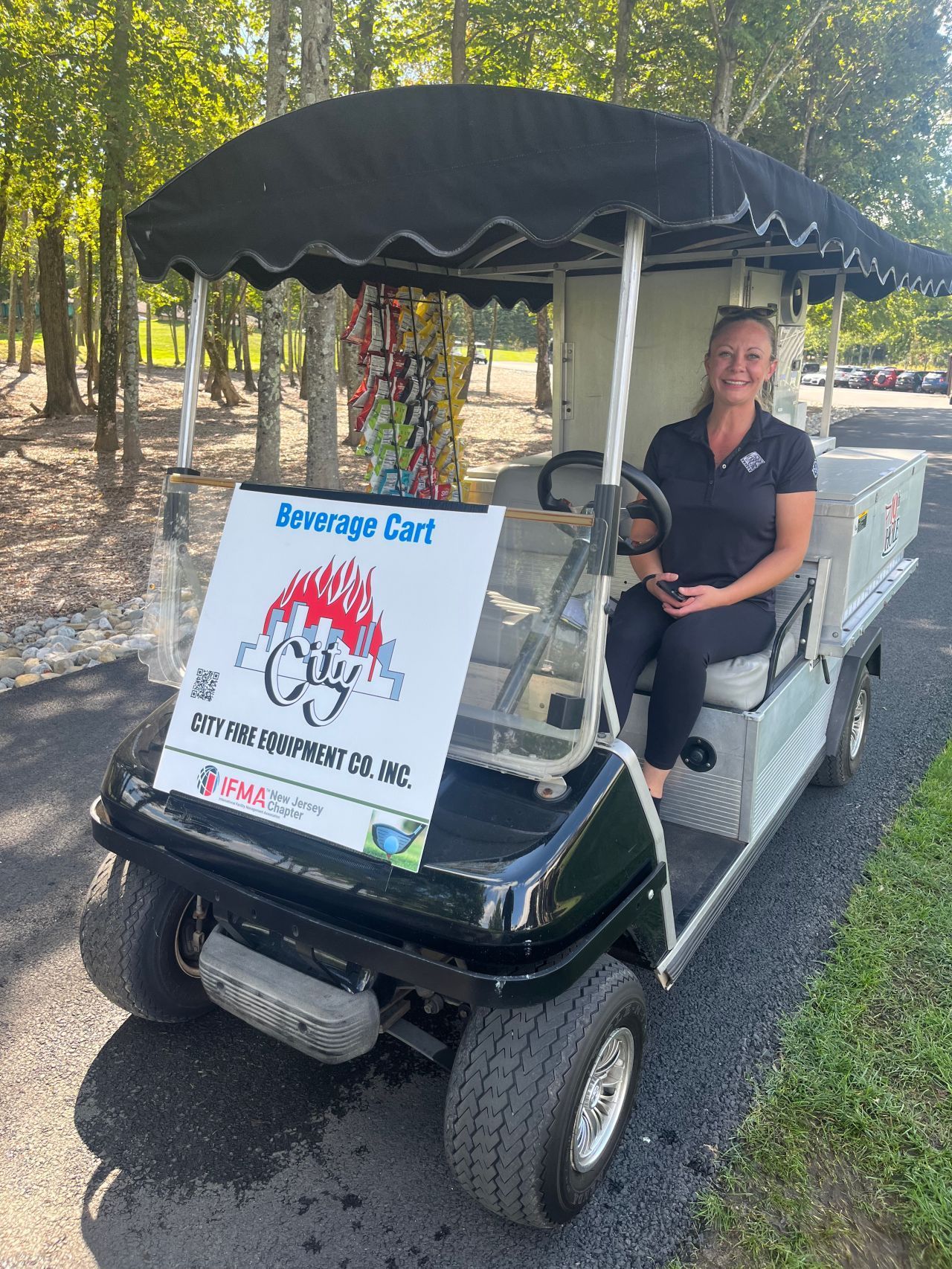 A woman is sitting in a golf cart with a sign on it.