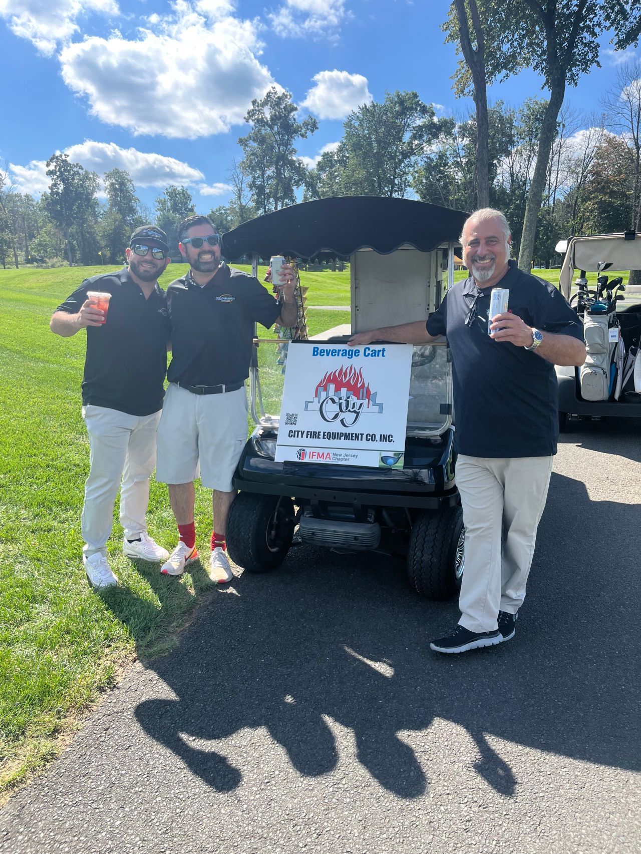 Three men are standing next to a golf cart on a golf course.
