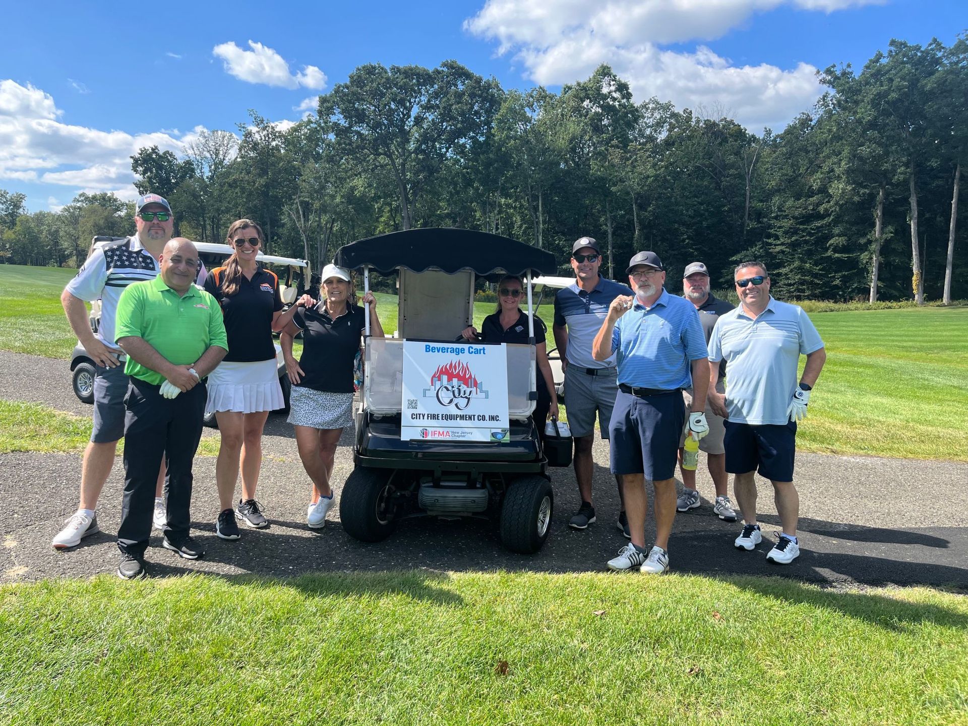 A group of people standing next to a golf cart on a golf course.