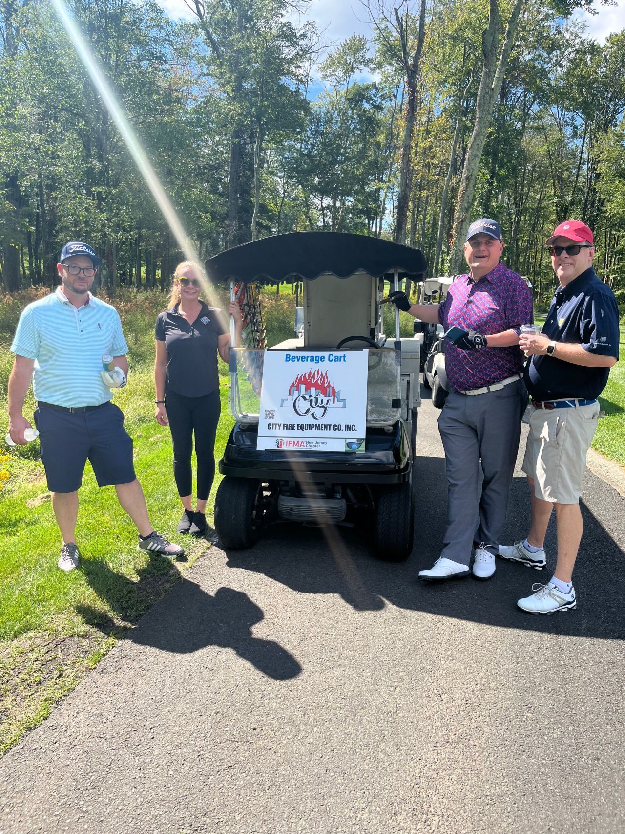 A group of people standing next to a golf cart on a golf course.