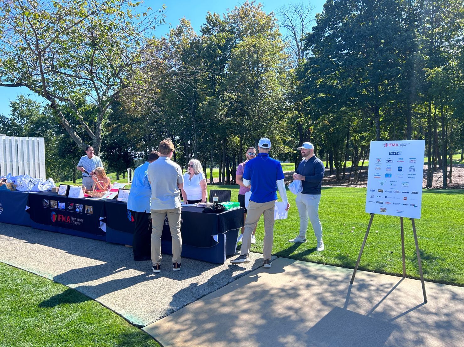 A group of people are standing around a table on a golf course.