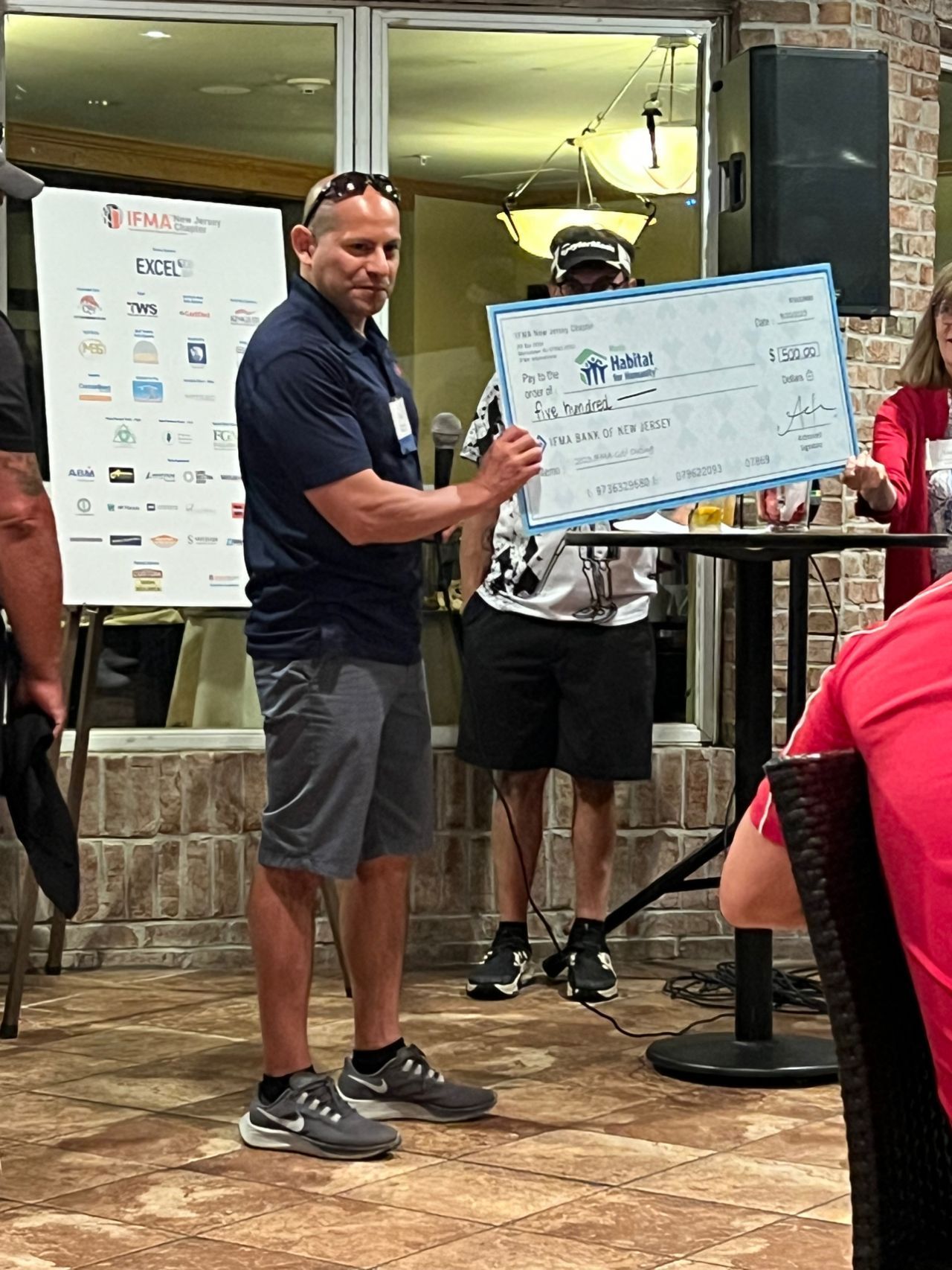 A man is holding a large check in front of a group of people.