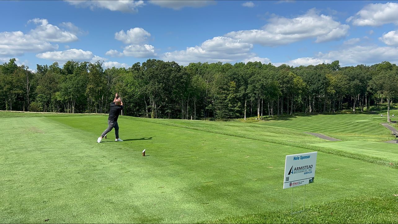 A man is swinging a golf club on a golf course.