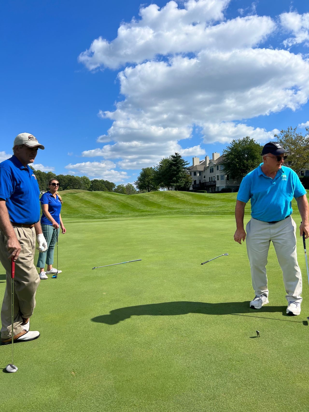 A man in a blue shirt is standing on a golf course