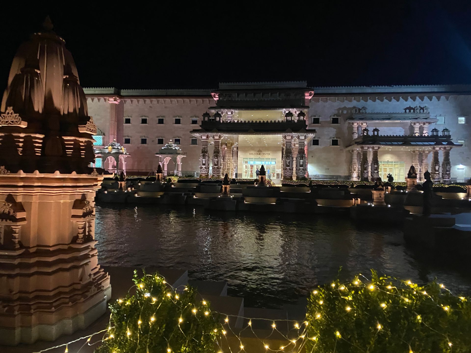 A large building is lit up at night next to a body of water.