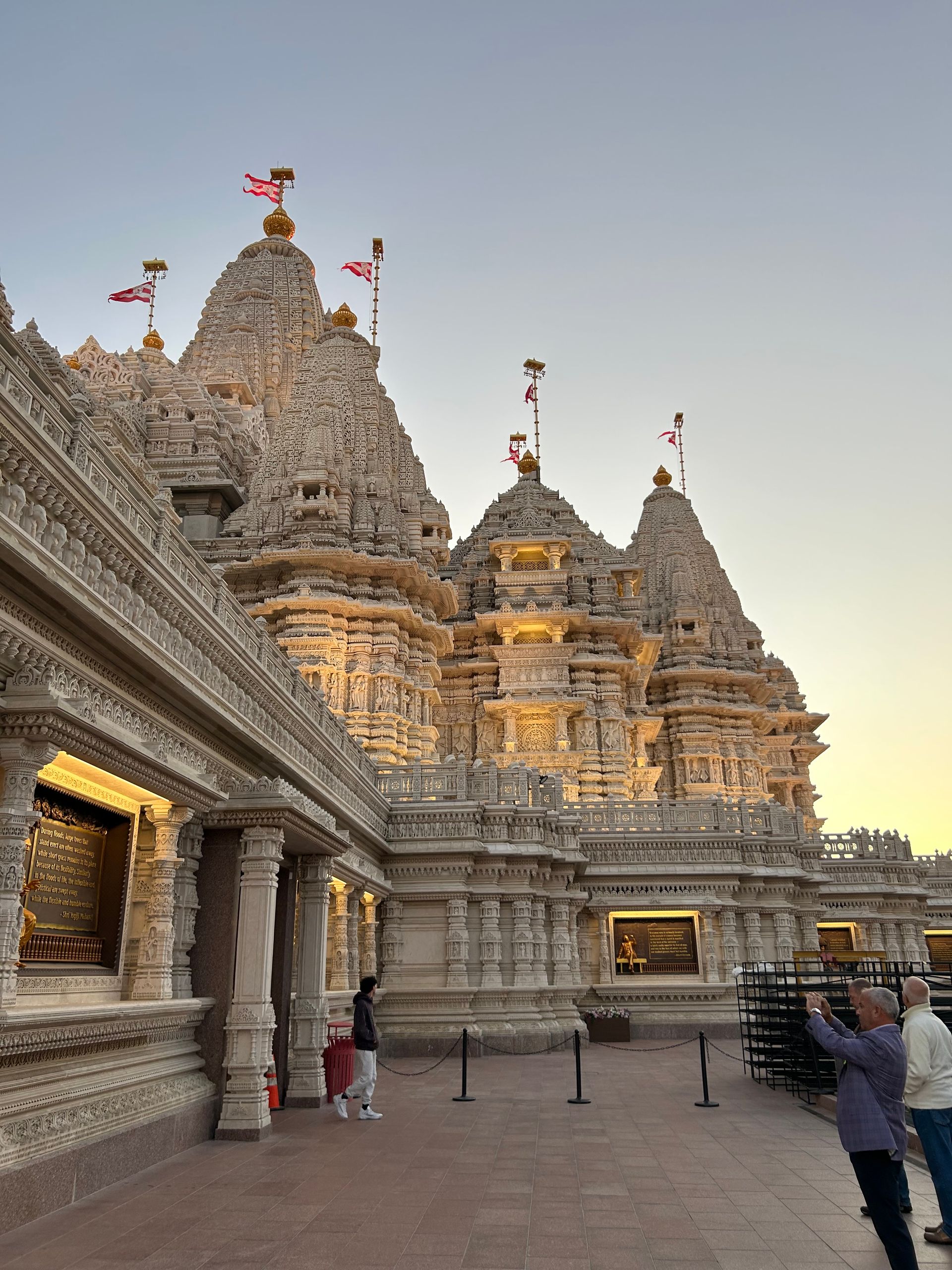 A man is taking a picture of a temple at sunset.