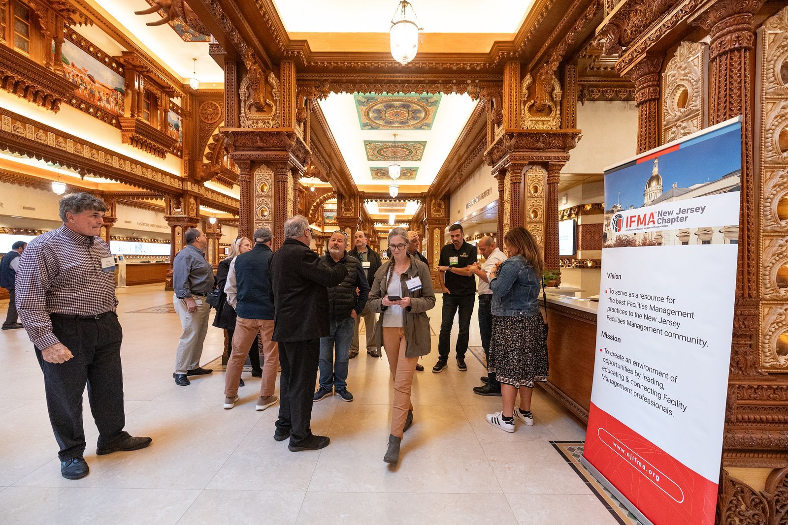 A group of people are standing in a hallway next to a sign.
